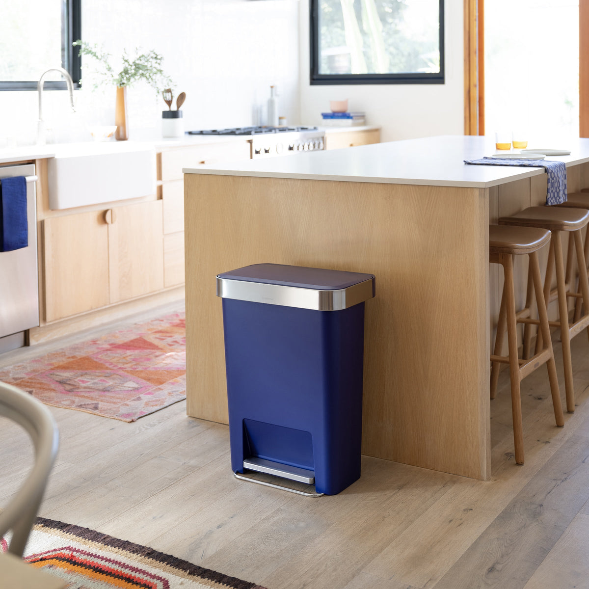 Simplehuman 45L Hybrid Step Can, Ultra Violet, hands-free pedal, resting against a light wood kitchen island.