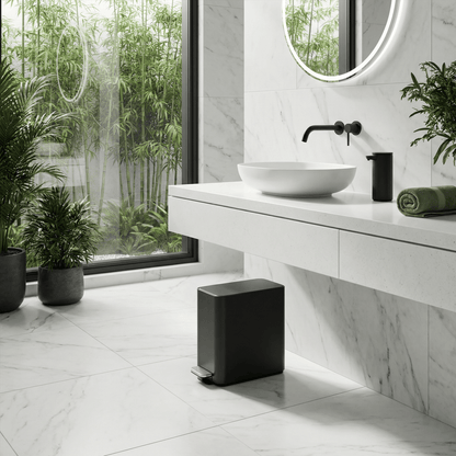 Simplehuman's 9L Slim Step Can in Matte Black in a bright and modern kitchen setting white marble floors, walls, and fresh plants. This image also feature Simplehuman's Matte Black Sensor Pump.