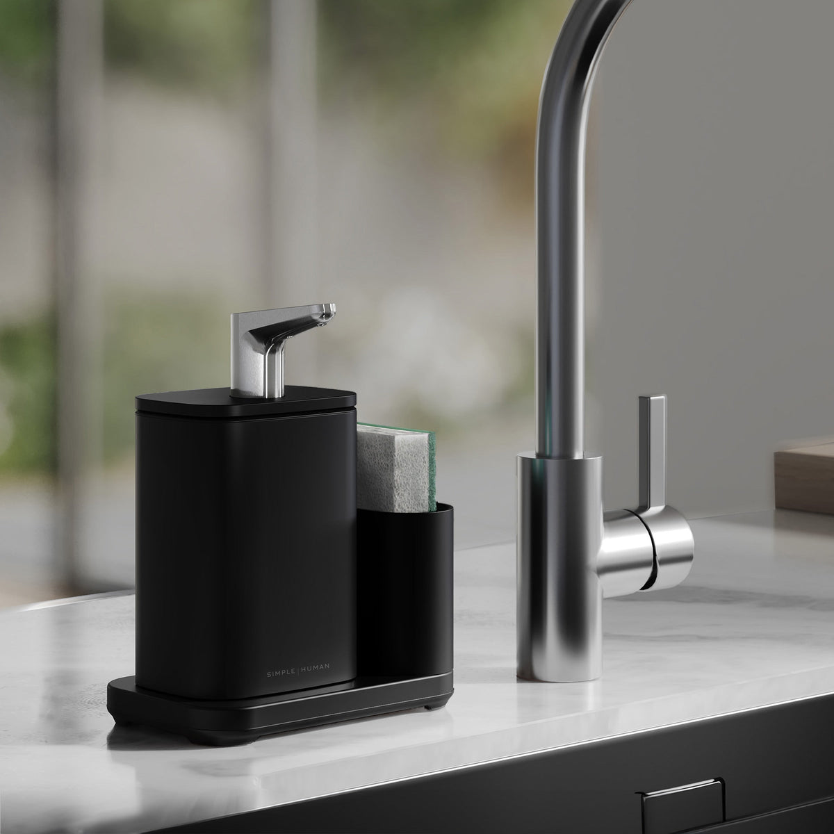 Simplehuman Matte Black Pulse Pump with caddy on kitchen sink edge, sponge in caddy on marble counter top.