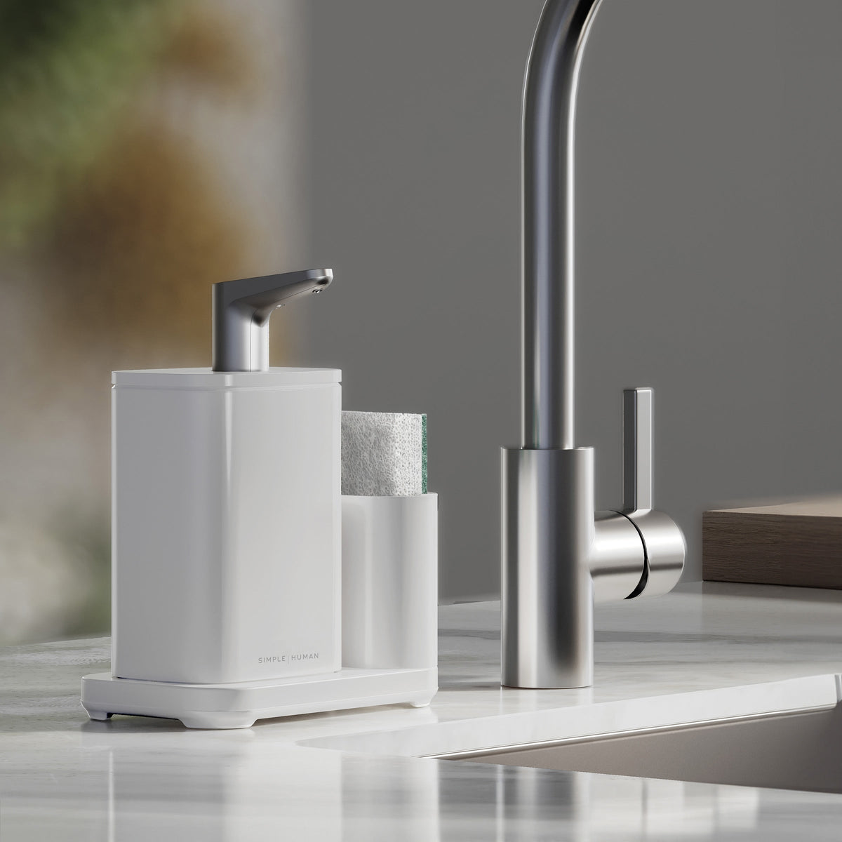 Simplehuman White Pulse Pump with caddy on kitchen sink edge, sponge in caddy, on marble countertop.